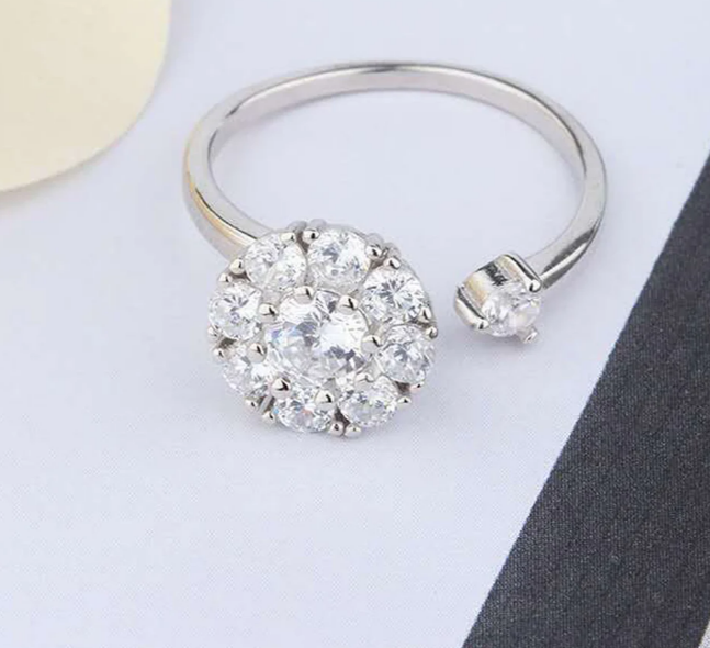 Silver ring with a diamond cluster on a light gray background