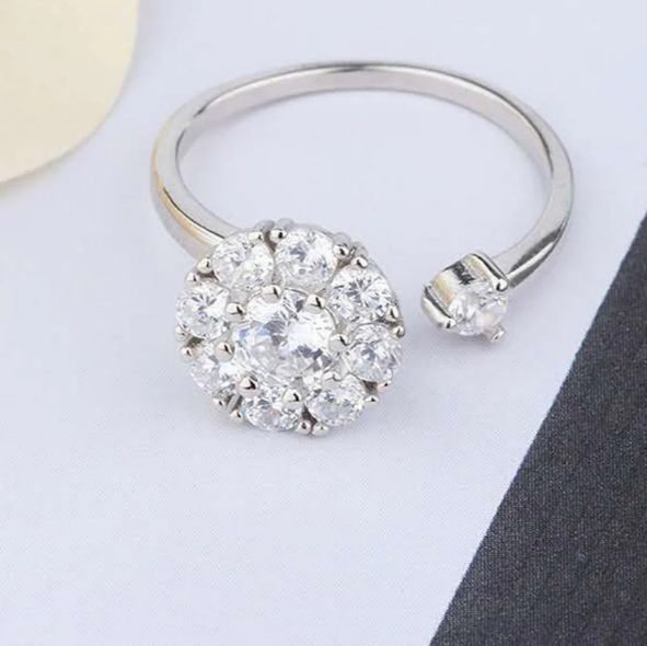Silver ring with a diamond cluster on a light gray background