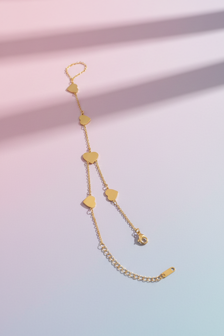 Gold bracelet with heart-shaped links on a gradient pink and blue background