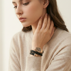 Woman wearing a beige sweater and multiple bracelets on a neutral background