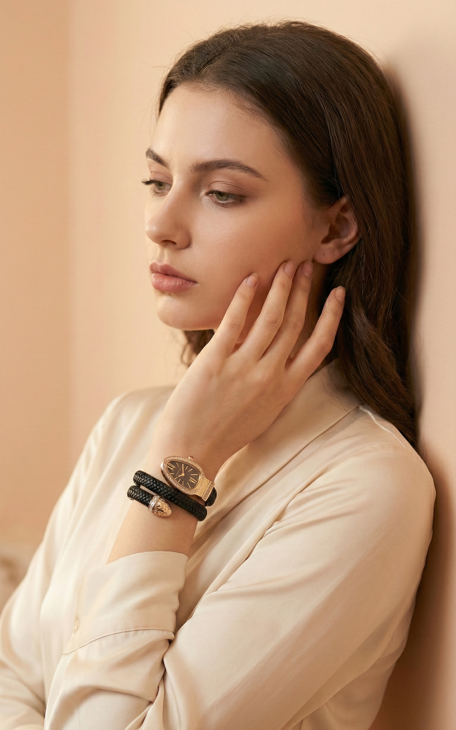 Woman wearing a watch and bracelet against a beige background