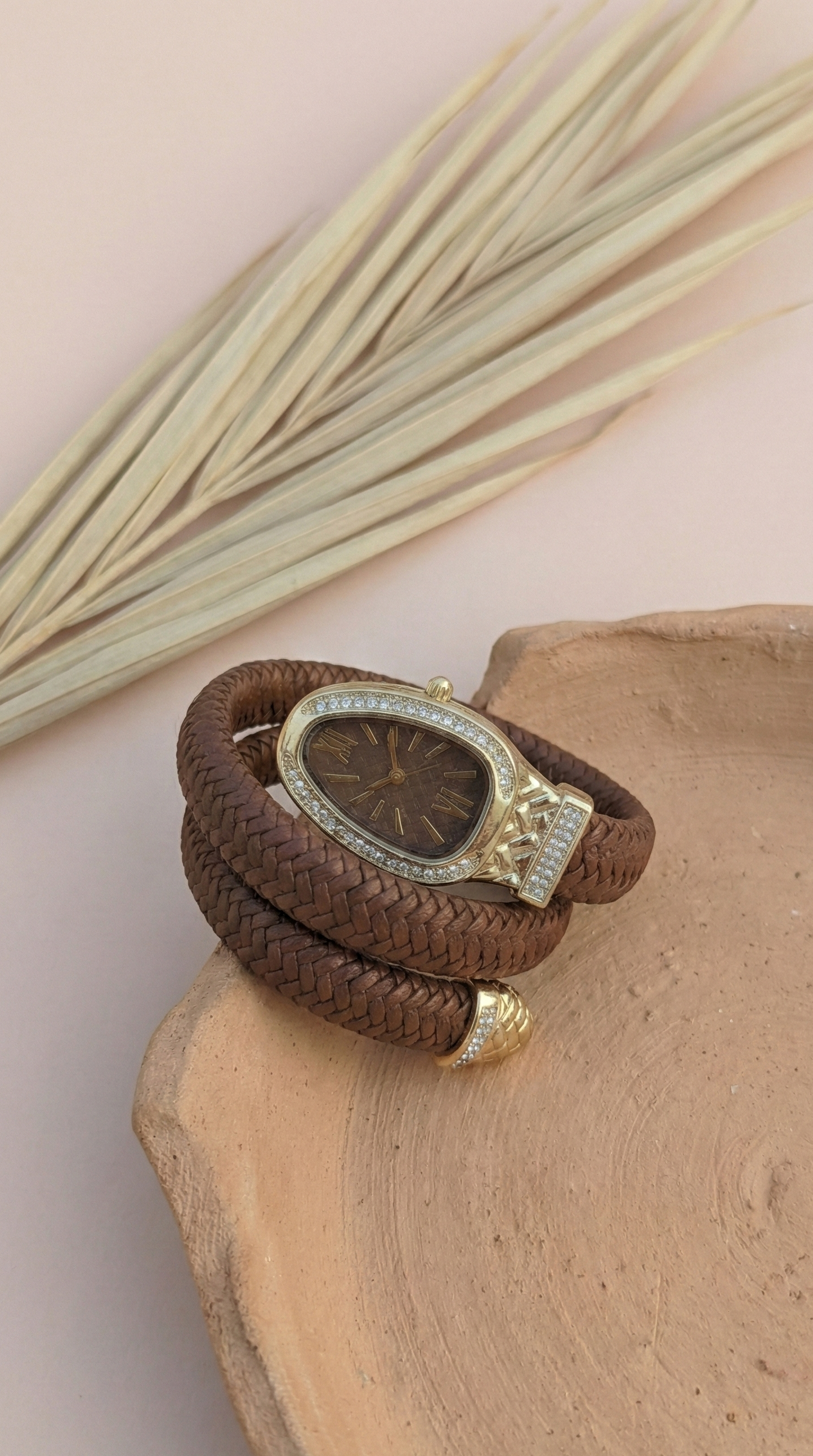 Brown leather bracelet with gold accents on a wooden surface