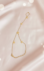 Gold bracelet with star-shaped links on a soft pink background