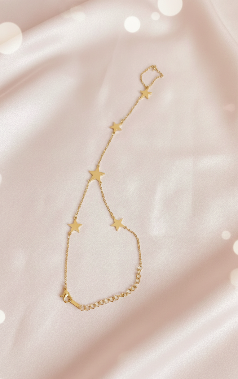 Gold bracelet with star-shaped links on a soft pink background