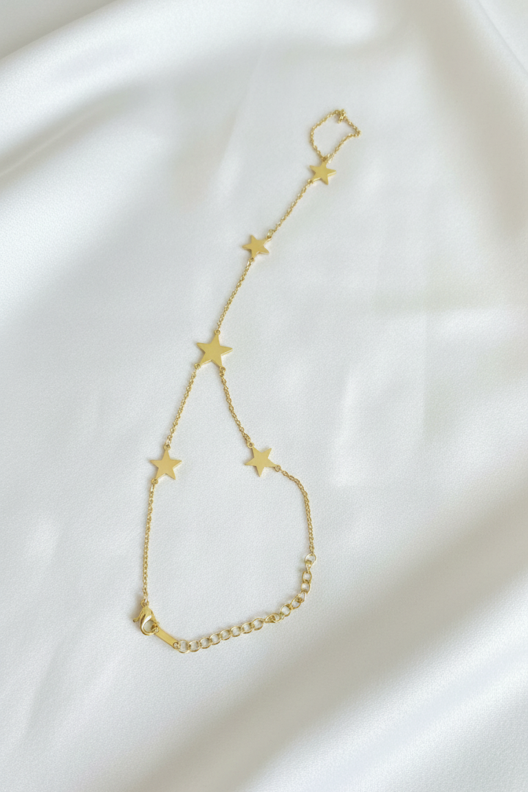 Gold bracelet with star-shaped charms on a white fabric background
