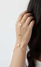 Gold star bracelet on a hand with a white background