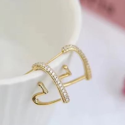 Small Gold-Tone Crystal-Accented Heart Earrings - ORYX TREND EaringThese stylish heart-shaped earrings are crafted in a bright gold tone and feature a partial row of shimmering clear stones along the top edge. The open-frame design keeps them lightweight and easy to wear. They are an ideal choice for adding a little sparkle and warmth to your look.Default Title#
