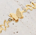 Dainty Gold Butterfly Cuff Bracelet with Crystal Accents - ORYX TREND BraceletsAn elegant gold-tone bangle bracelet featuring a central, intricately textured butterfly charm. The rest of the cuff is adorned with delicate cutout butterfly shapes, interspersed with small, sparkling crystal accents. This piece uses a durable, hinged clasp for secure and comfortable wear. It beautifully symbolizes transformation and grace, making it a perfect statement piece or a thoughtful gift.Default Title#