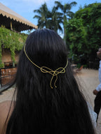 Person with long black hair wearing a gold hair accessory outdoors