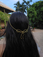 Person wearing a gold hair accessory with a bow design outdoors.