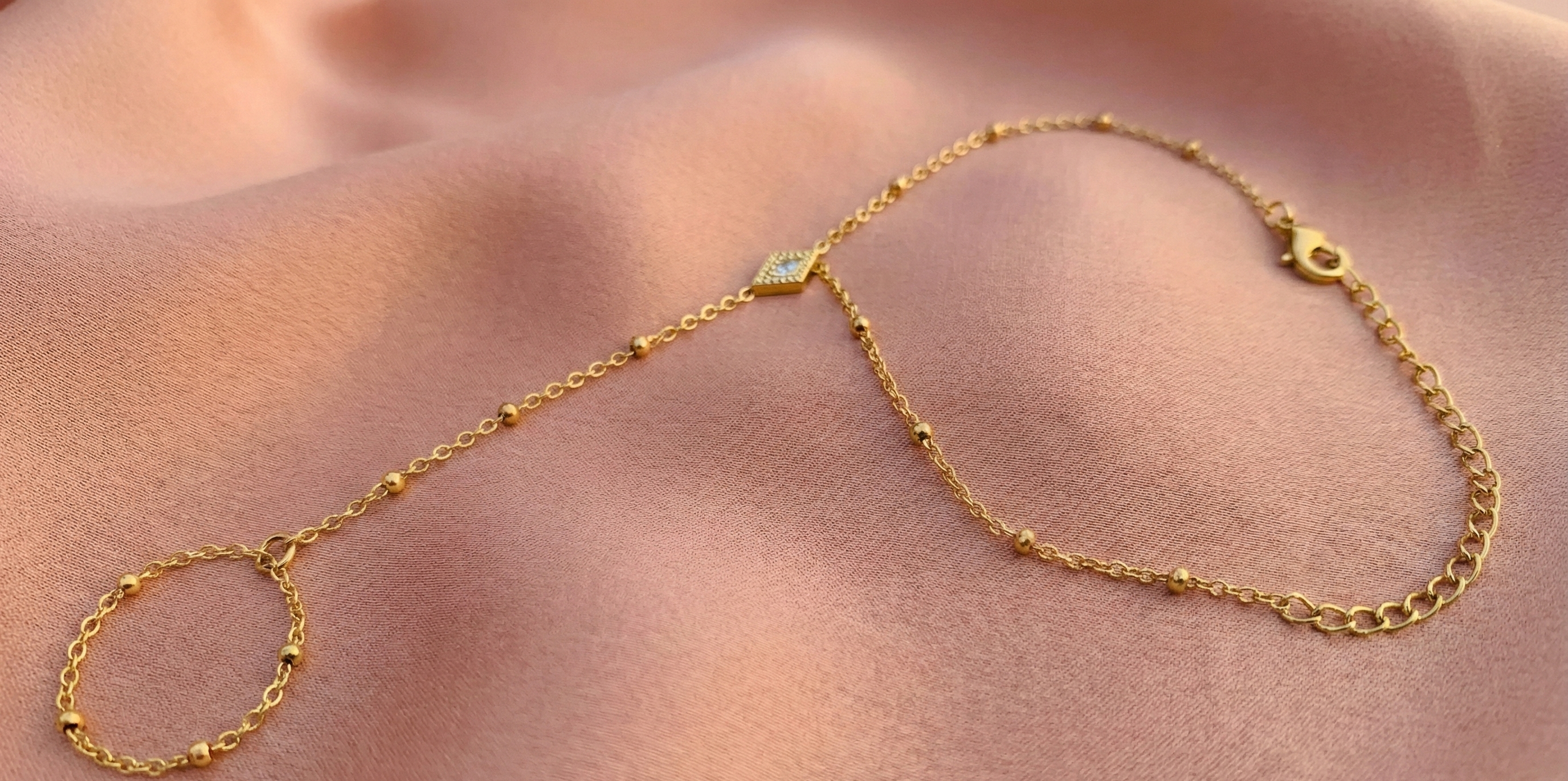 Diamond Shape Hand Harness Bracelet - ORYX TREND Hath PhoolThis delicate Hath Phool (Hand Flower) is a modern take on a classic piece of South Asian jewelry. Featuring a slim chain of polished gold beads connecting a single finger ring to an elegant bracelet, it's accented by a central diamond-shaped charm. This minimalist hand harness is perfect for bridesmaids, festivals, or adding a unique, elegant touch to everyday wear. Style: Hath Phool, Hand Harness, Minimalist, TraditionalDefault Title#