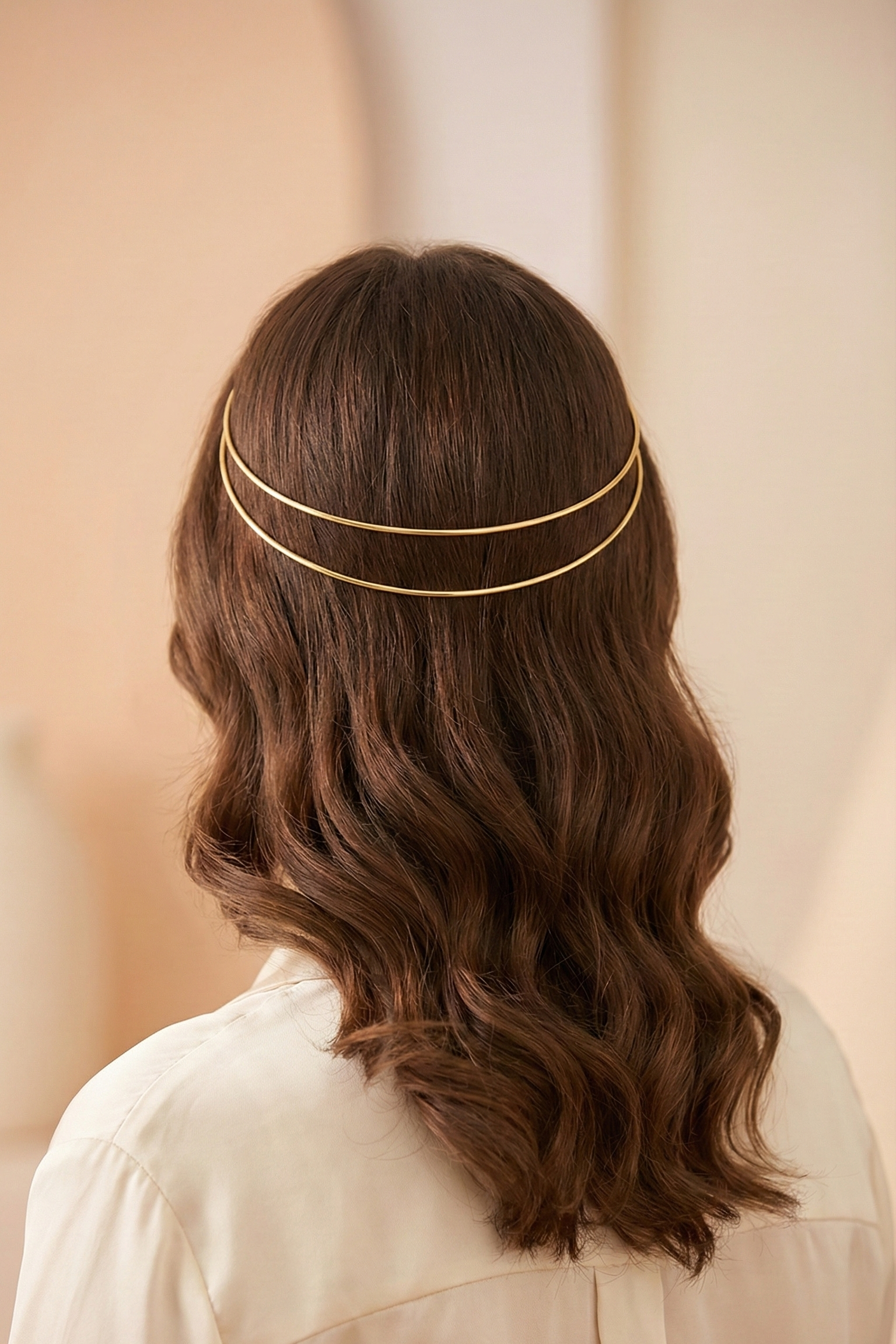 Person wearing a gold headband with wavy hair against a neutral background
