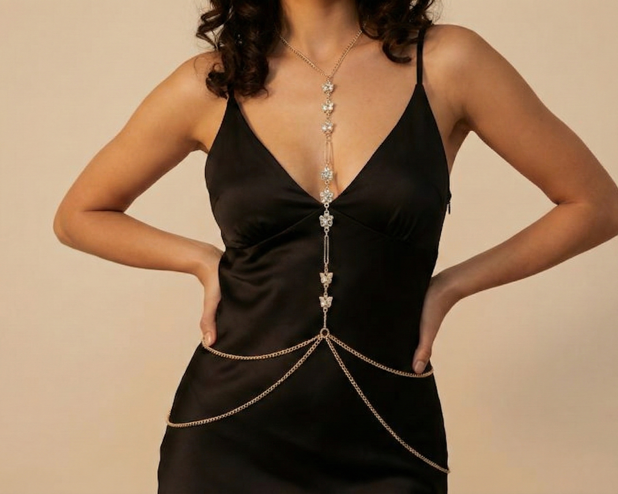 Woman wearing a black dress with a decorative chain detail on a beige background