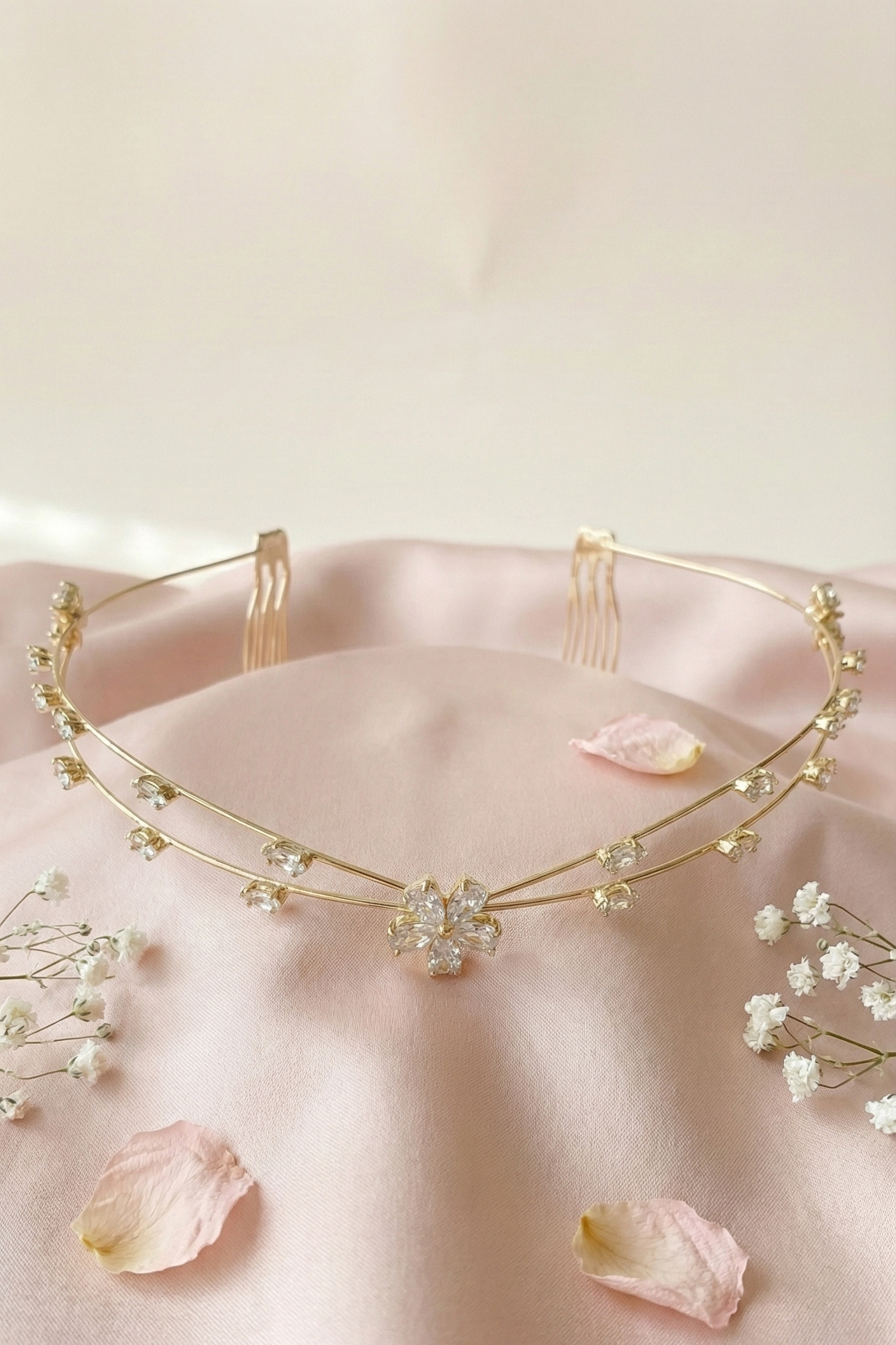 Gold necklace with floral elements on a pink fabric background