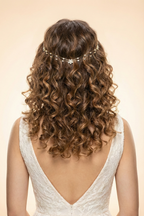 Woman with curly hair wearing a delicate headpiece, back view, on a beige background