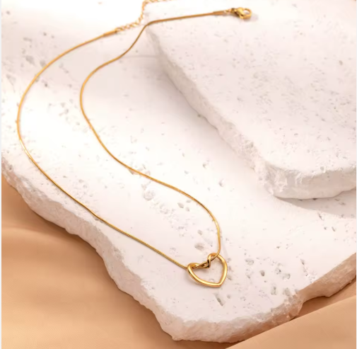 Gold heart-shaped necklace on a textured white surface