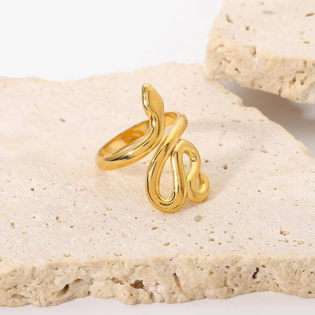Gold ring with a unique design on a beige stone surface