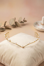 Gold headband with pearls on a beige pillow