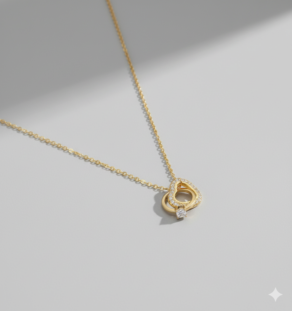 Interlocking Hearts Gold-Tone Necklace with Crystal Pavé - ORYX TREND NecklaceA delicate and sentimental necklace featuring two beautifully interlocking rings. One ring is a heart shape completely adorned with sparkling crystal pavé stones, while the other is a smooth, polished ring. This design symbolizes infinite love and unbreakable connection. The pendant is suspended from a fine, gold-tone chain, making it an ideal gift for an anniversary, Valentine's Day, or just to show someone you careDefault Title#