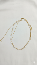 Gold necklace with pearls on a light gray background
