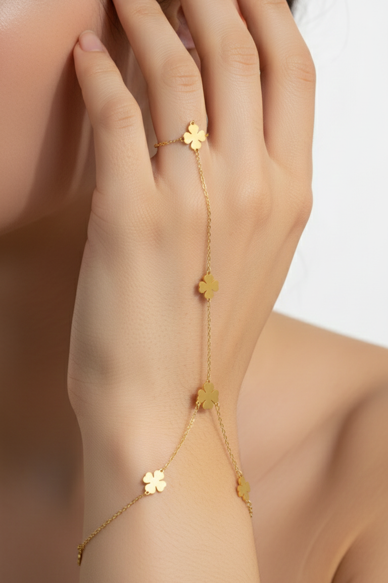 Gold bracelet with clover-shaped charms on a hand against a white background