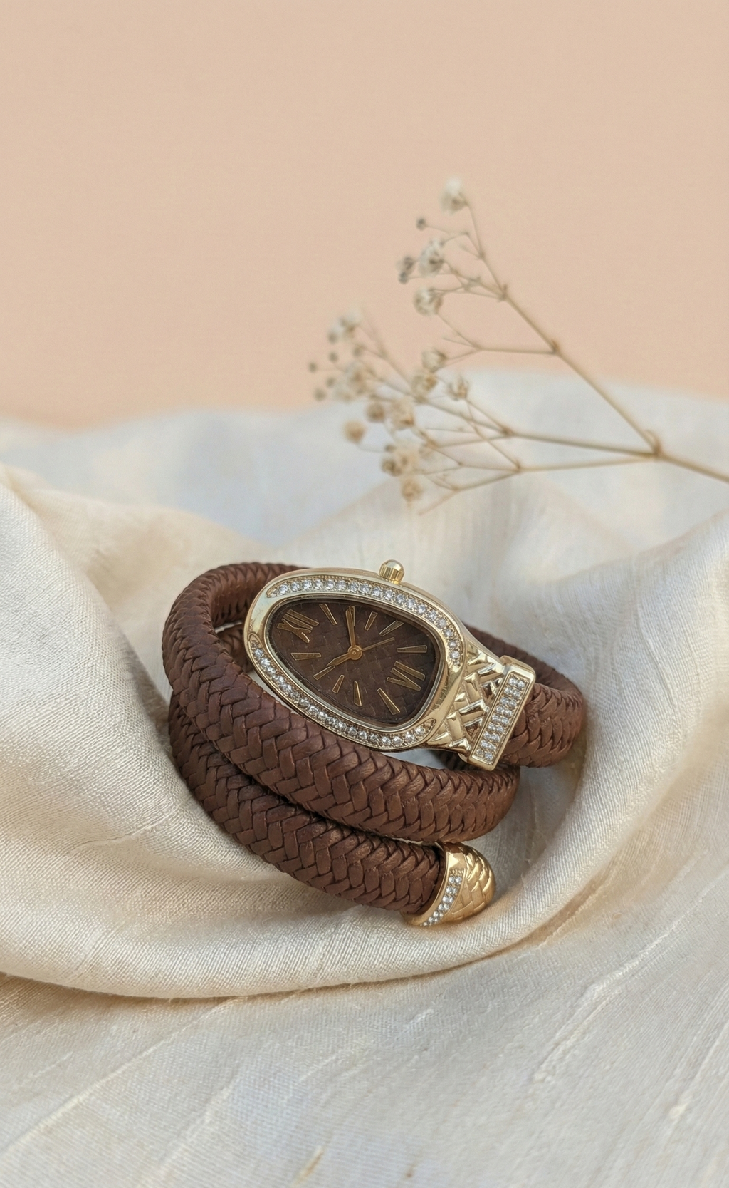 Brown leather bracelet with decorative clasp on a light fabric background