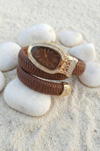 Brown braided bracelet with gold accents on a white stone surface