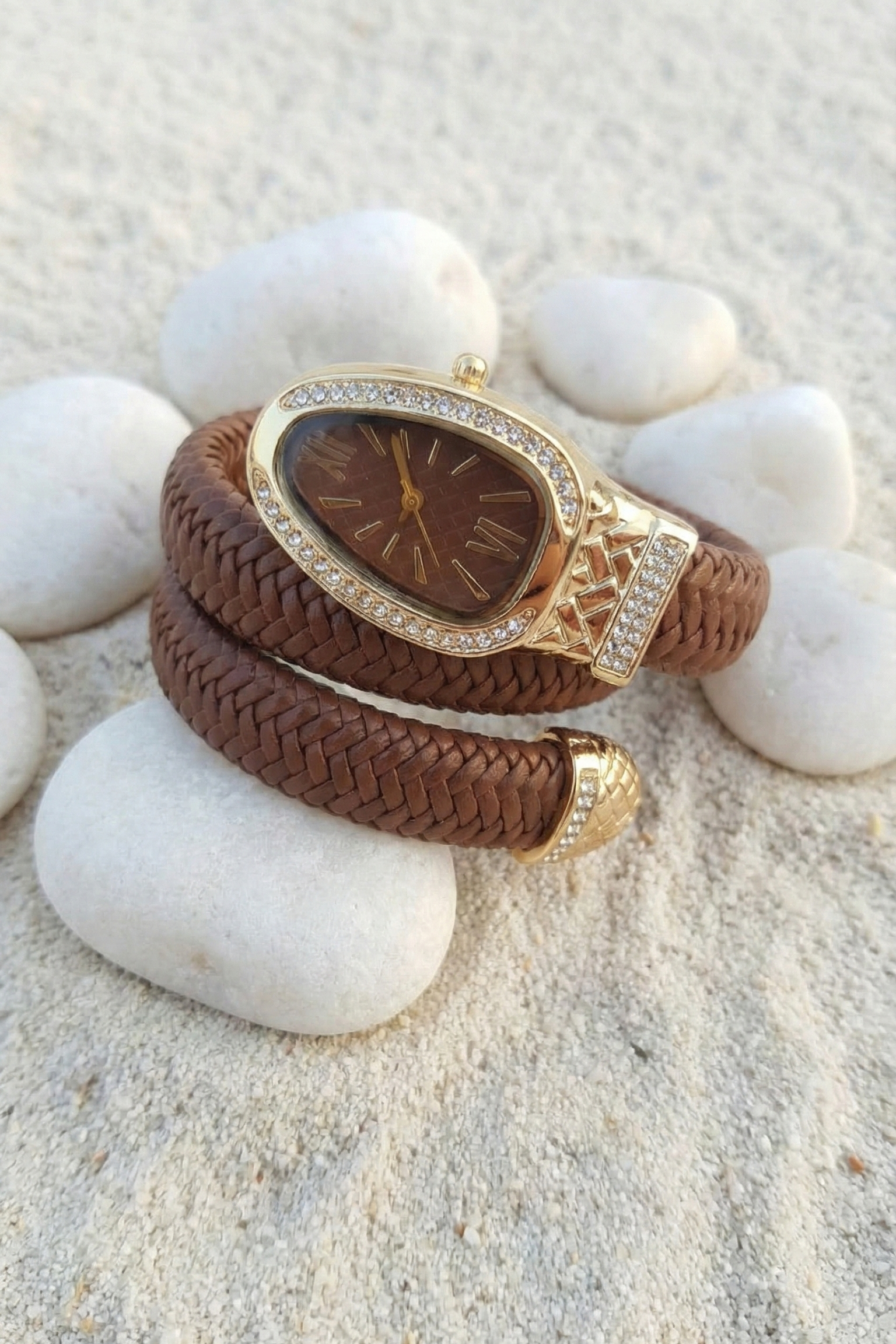 Brown braided bracelet with gold accents on a white stone surface