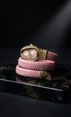 Pink braided bracelet with gold clasp on a dark surface