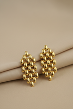 Gold geometric earrings on a beige surface