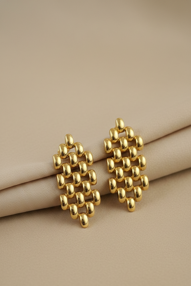 Gold geometric earrings on a beige surface