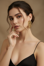 Woman wearing gold earrings against a beige background