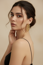 Woman wearing gold earrings with a neutral background