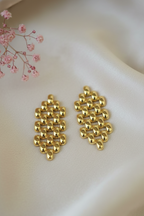 Gold earrings on a light pink fabric background with pink flowers.