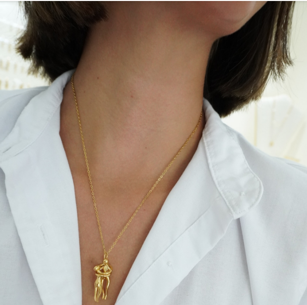 The Embrace Necklace: Gold-Tone Hug Pendant - ORYX TREND NecklaceA beautifully artistic necklace featuring a minimalist pendant design that captures the tender moment of an intimate embrace. The gold-tone pendant depicts two stylized figures locked in a hug, symbolizing love, connection, comfort, and friendship. Suspended from a delicate gold-toned chain (perhaps a flat link or paperclip style), this unique piece makes a deeply personal and meaningful gift for a loved one.Default Title#