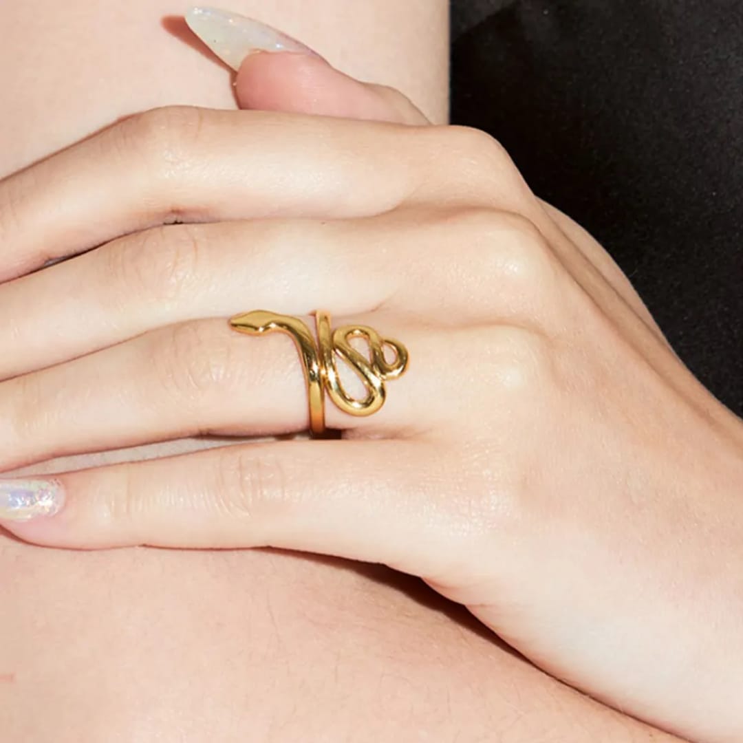 Gold ring on a person's finger with a plain background
