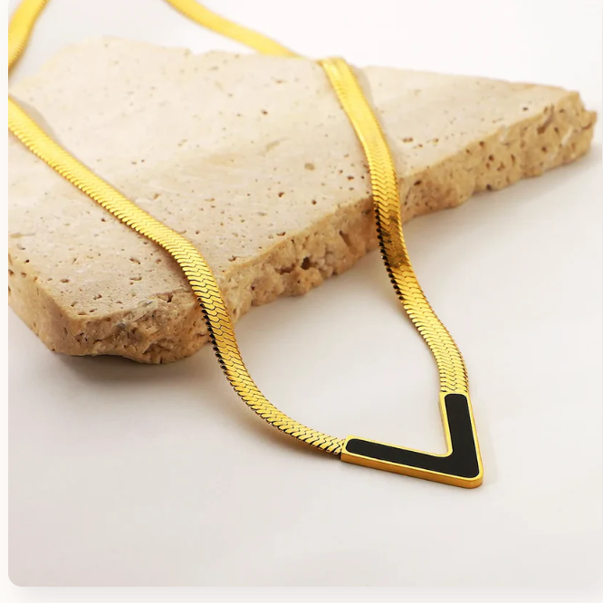 Gold necklace with a black accent on a stone surface
