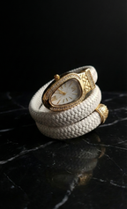 White braided leather bracelet with gold watch face on a dark reflective surface
