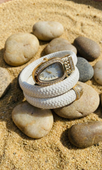 Watch wrapped in white cord on stones with sand background