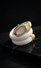 Gold watch with a white woven strap on a dark surface